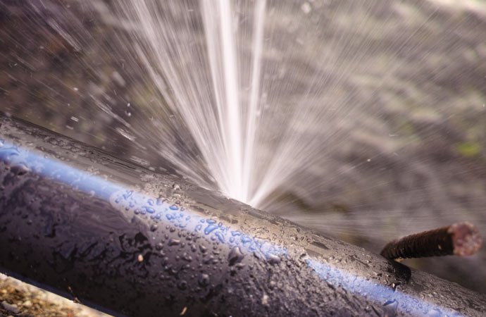 A burst water pipe spraying water.
