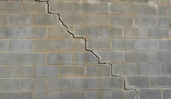 concrete wall with a significant diagonal crack indicating structural damage